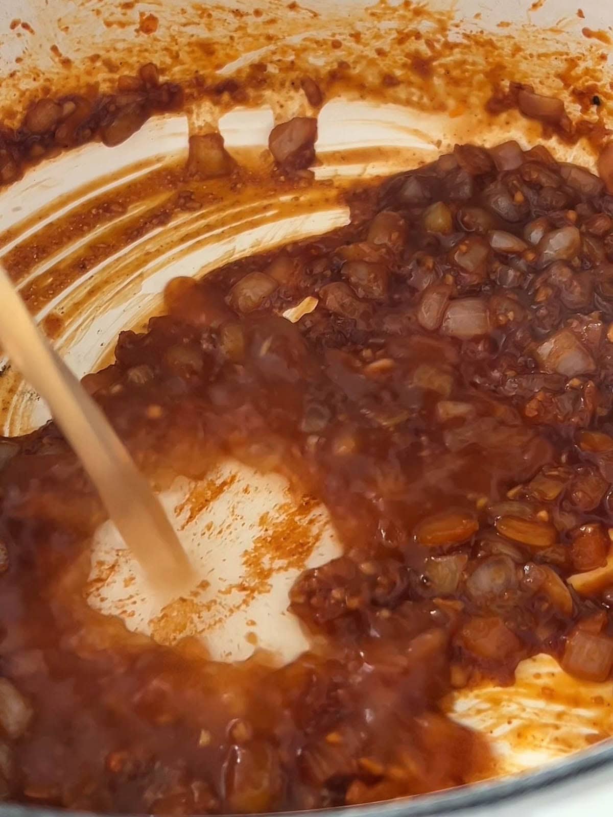 Gochujang, onion, garlic mixture with beef broth and soy sauce in a dutch oven.