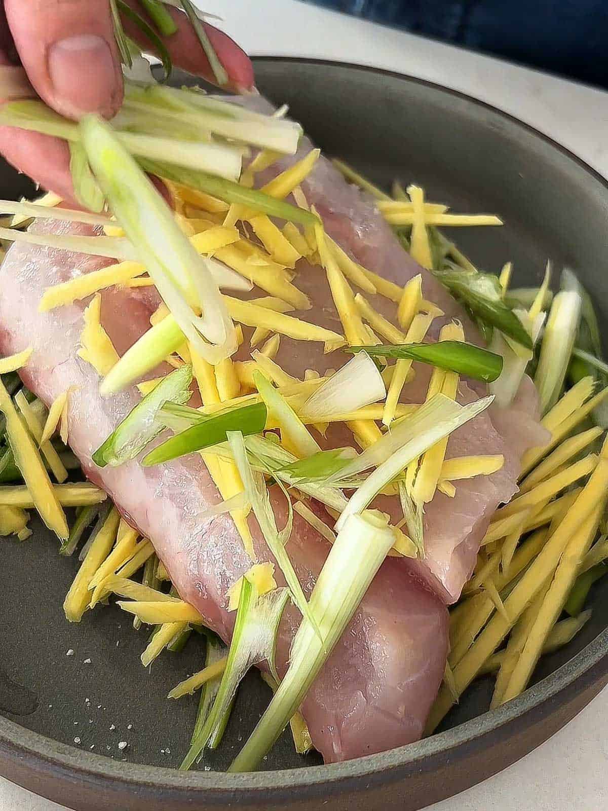 Julienned ginger and scallions over raw fish.