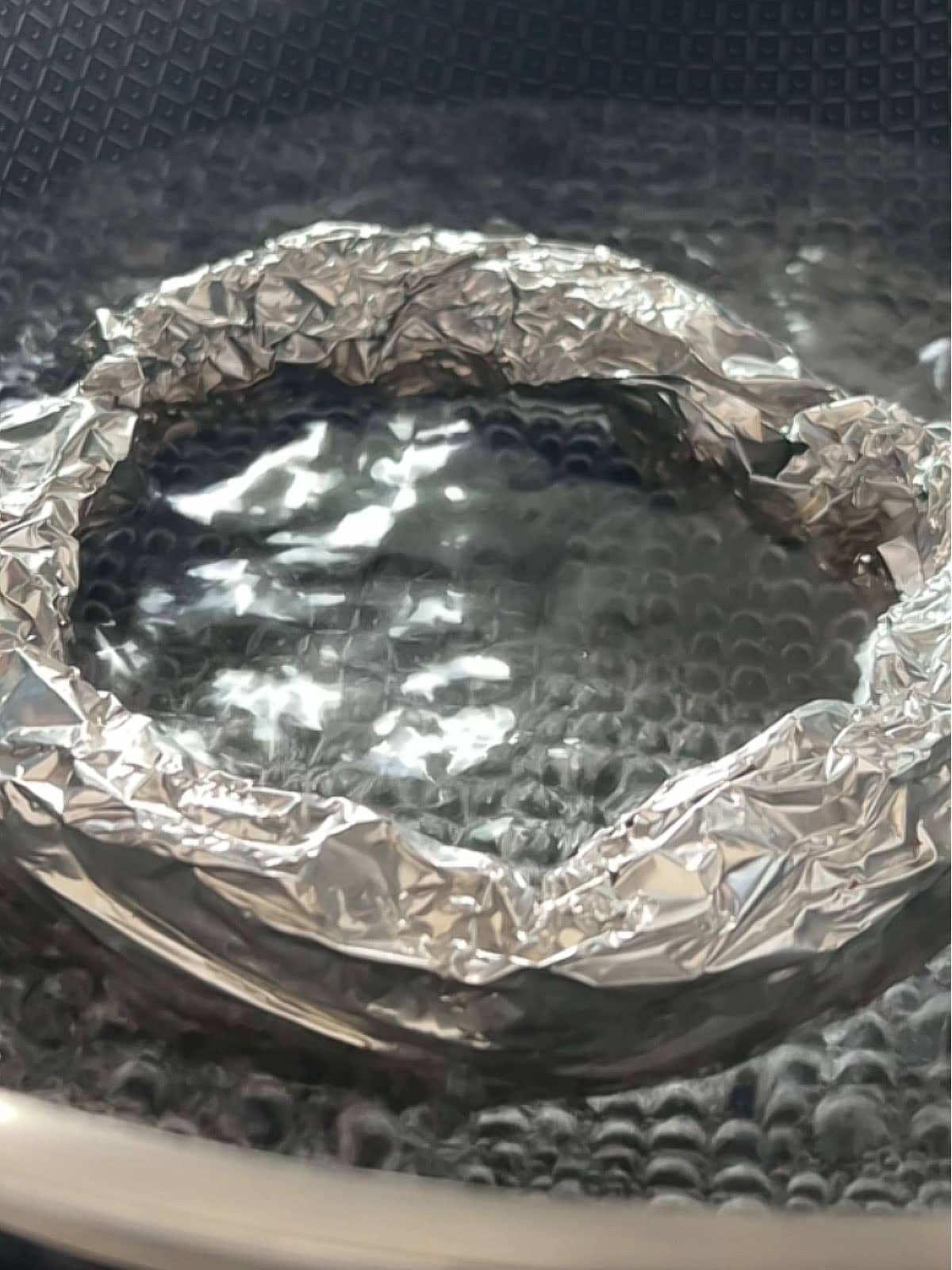 Makeshift steamer using foil in a pot of water.
