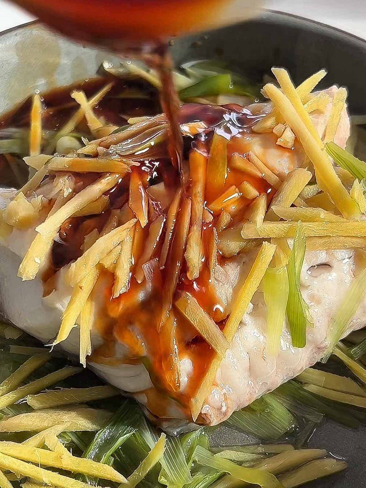 Soy sauce mixture poured over steamed fish, scallions, and ginger.