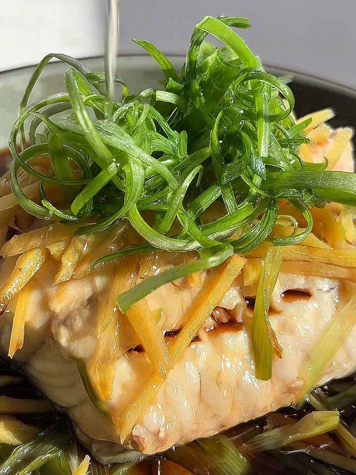 Hot oil poured over scallion greens and ginger over cooked steamed fish.