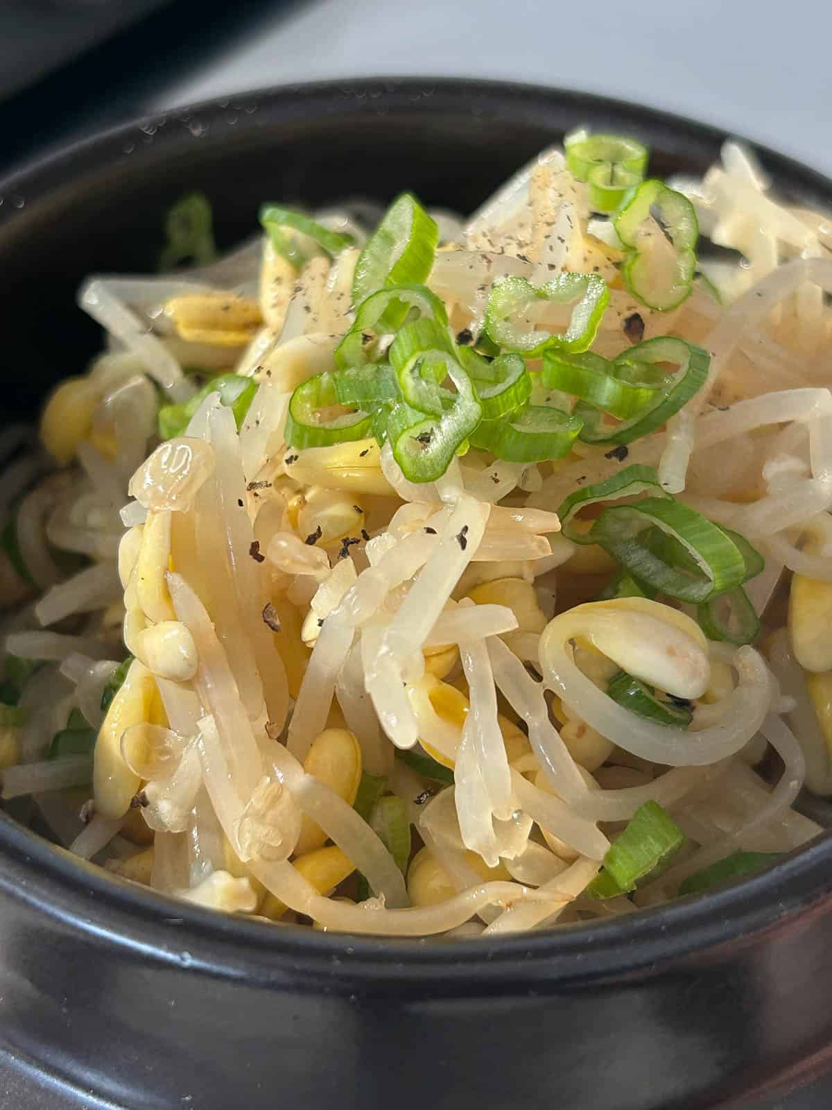 Blanched soybean sprouts topped with black pepper and green scallions.
