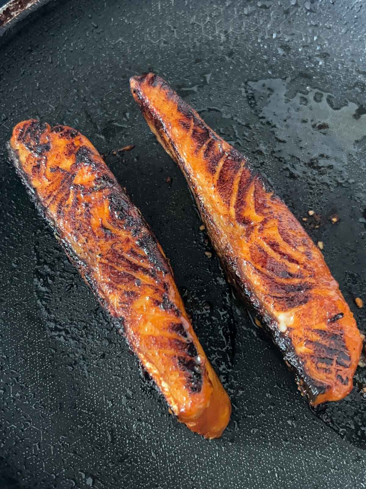 Salmon seared and caramelized in a pan.