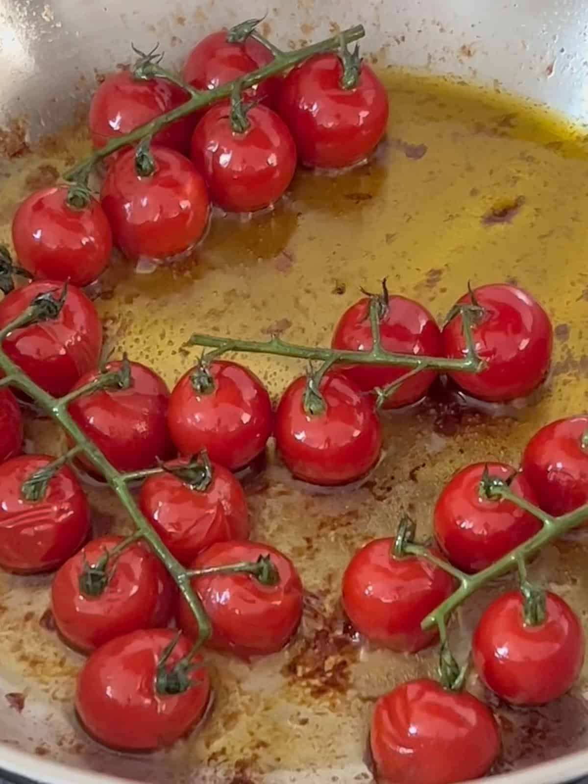 Cherry tomatoes roasting in a pan.
