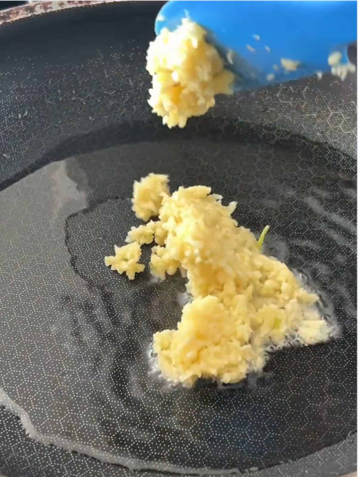 Close-up of finely chopped garlic being added to a pan with oil.