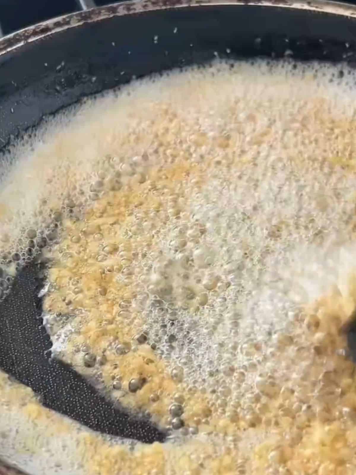 Close-up of minced garlic frying in hot oil until lightly golden.