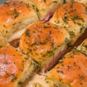 Baked ham and cheese sliders brushed with garlic butter.