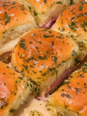 Baked ham and cheese sliders brushed with garlic butter.