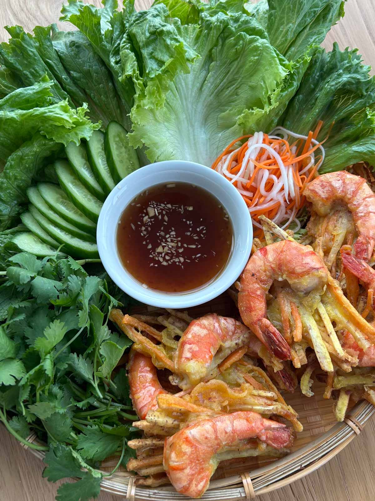 Banh tom chien platter with veggies, fresh herbs, fish sauce and pickled daikon and carrots.