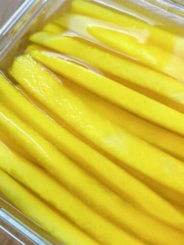 Close up of yellow pickled radish in a container.