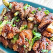 Vietnamese yakitori chicken skewers with a sticky fish sauce caramel glaze, topped with black pepper and sliced scallions on a plate.