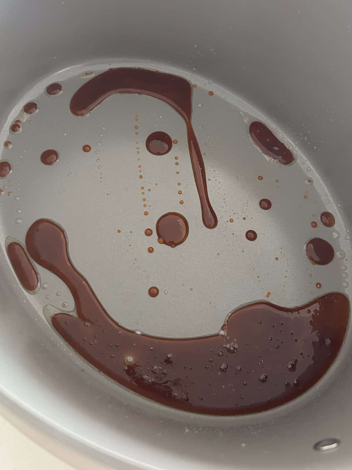 Dark amber caramelized sugar and oil in a pot.