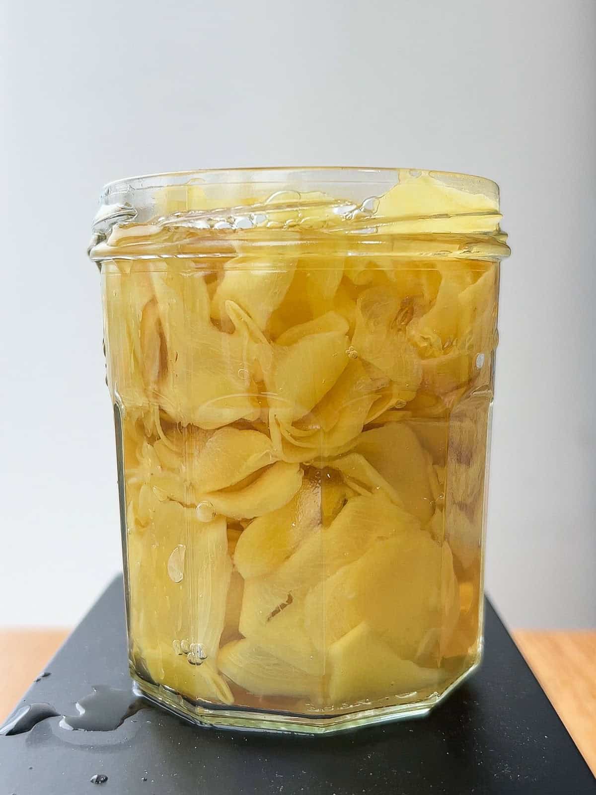 Glass jar of pickled ginger in brine.